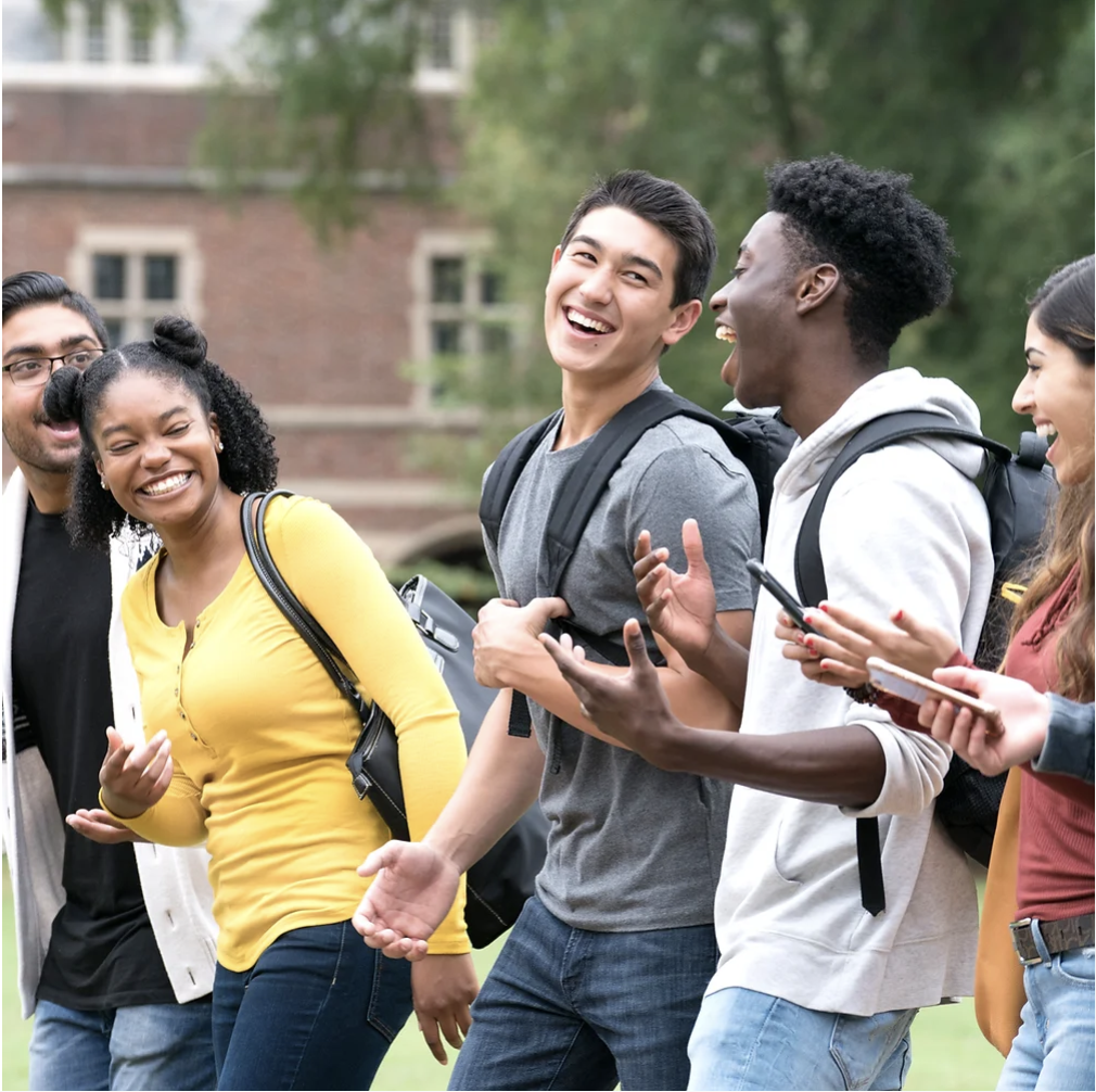 A group of students laughing together outside on campus